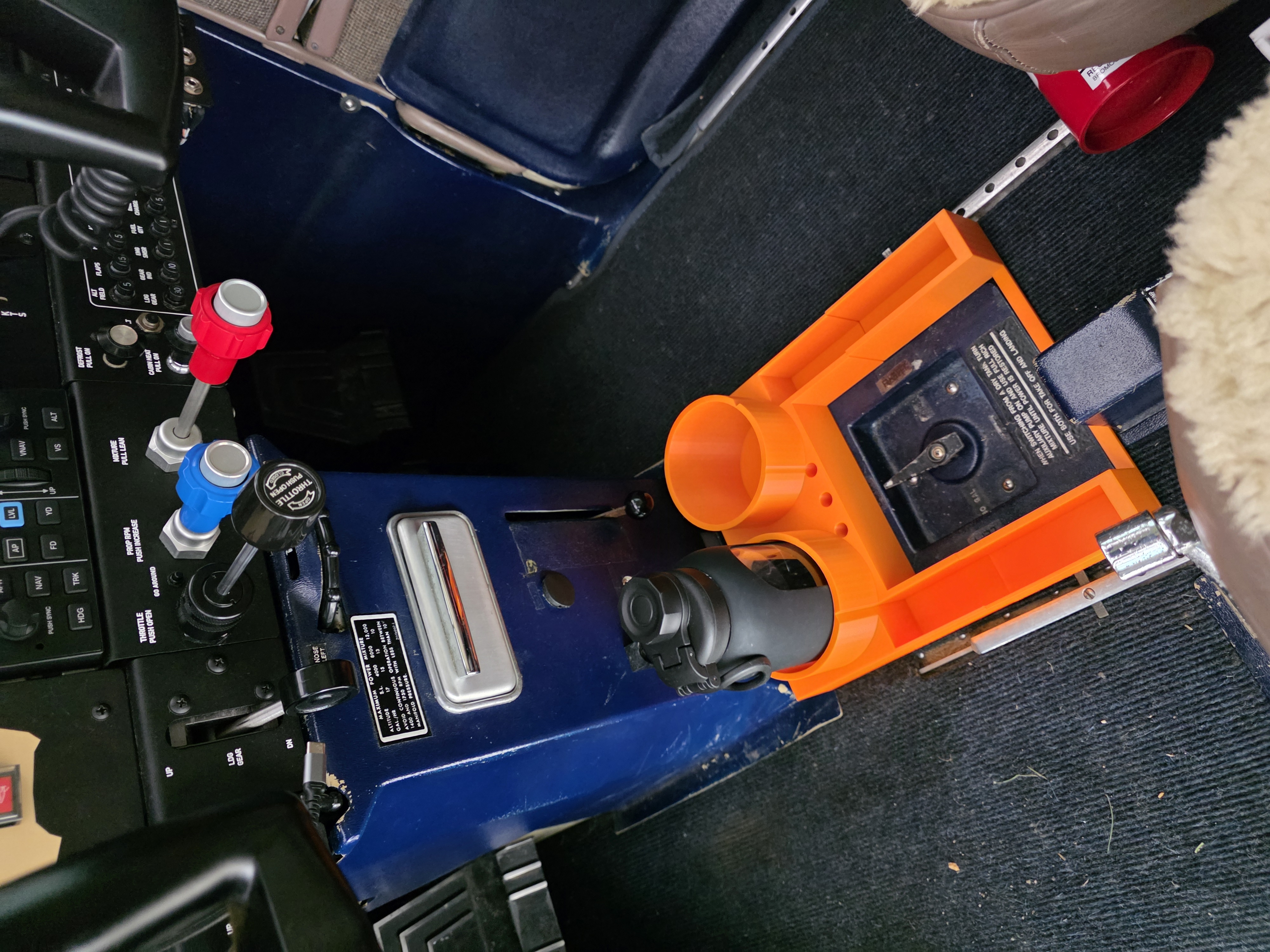 A custom orange cockpit organizer fitted in a Cardinal, holding a water bottle, a cup, and tools
